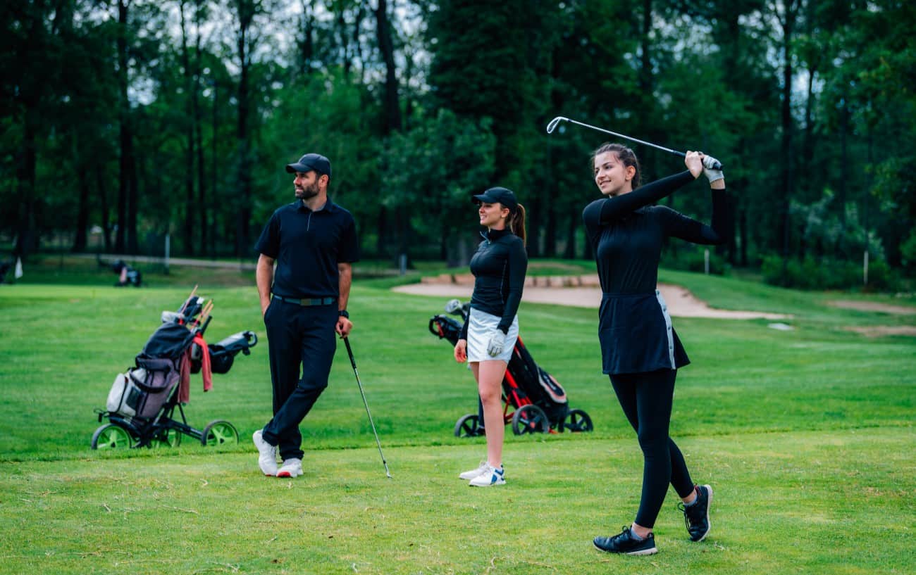 Golf Foot Placement - Your Foot Position for Golf Explained 10 a golfer makes a swing while two other golfers watch